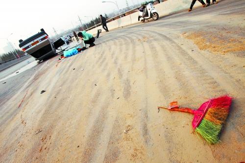 被撞的環(huán)衛(wèi)工躺在地上，身上蓋著藍(lán)色布塊，現(xiàn)場除散落的汽車碎片外，還留有被撞斷的掃帚。