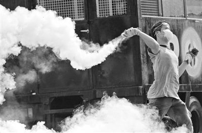 12月2日，泰國(guó)曼谷，一名反政府示威者在總理府附近向負(fù)責(zé)執(zhí)勤的警察投擲催淚彈。英拉請(qǐng)求示威者不要再試圖占領(lǐng)政府工作部門(mén)，不要逼迫政府工作人員選邊站。