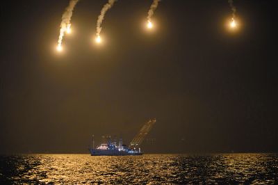 22日，搜救人員在照明彈的光亮下連夜搜救。