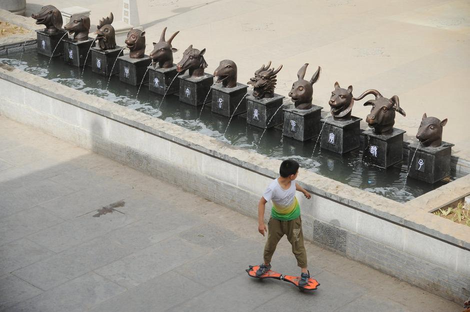 圖為一名市民從獸首旁經(jīng)過。