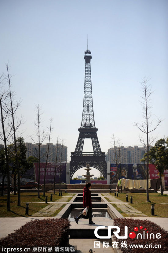 　2014年3月21日，杭州天都城，農(nóng)民在山寨埃菲爾鐵塔下耕作。圖片來源：東方IC