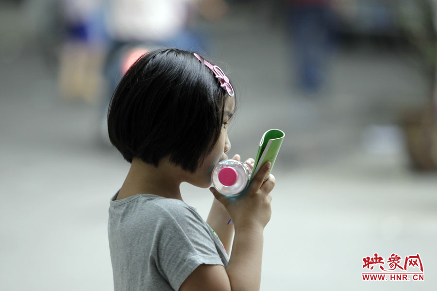 6月7日，鄭州回中考點(diǎn)，一名孩子拿著一瓶礦泉水，等待哥哥走出考場(chǎng)