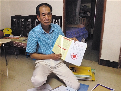 翻出一家網(wǎng)站贈予的“中國好人”證書，區(qū)少坤單膝跪在地上，“你看，我是中國好人啊?！?范春旭 攝