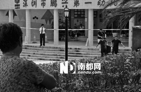 →7月19日，鵬興花園第一幼兒園門前，民警在現(xiàn)場進(jìn)行完勘查取證后，園長和保安的尸體被運(yùn)走。南都記者 徐文閣 攝