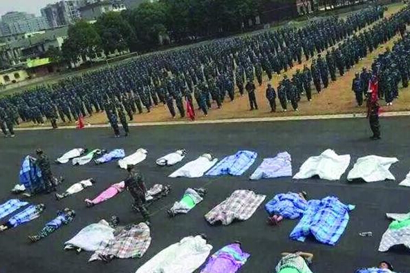 20多名女生躺在瀝青跑道上，身上嚴嚴實實地裹著棉被，接受太陽的照曬。