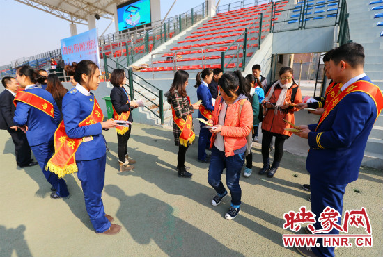 活動現(xiàn)場工作人員給同學(xué)們發(fā)放宣傳冊、環(huán)保袋。