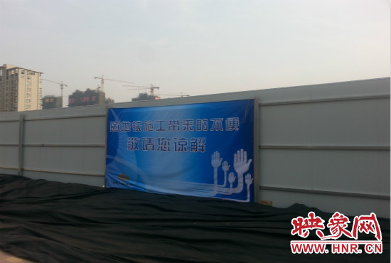 道路南側圍起了白色的圍擋，墻上標示著“因地鐵施工帶來的不便敬請您諒解”的提示牌。