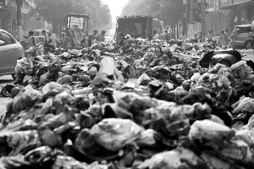 垃圾堆滿整個路口，環(huán)衛(wèi)工人們正在清理