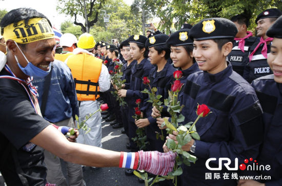 2013年12月03日,曼谷總理府與曼谷警署允許反政府示威民眾進(jìn)入,雙方進(jìn)入暫時(shí)“停戰(zhàn)”狀態(tài)迎接泰王生日。曼谷警察總署,女警們手持鮮花送給反政府示威民眾。圖片來(lái)源:Manish Swarup/東方IC