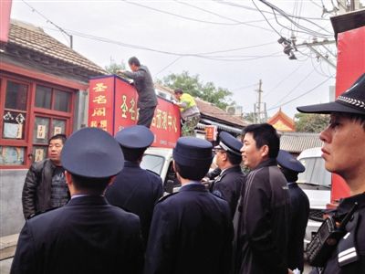 昨日下午,東城區(qū)工商、城管、公安等部門,對雍和宮附近的預(yù)測中心進(jìn)行清理整頓,站在車頂?shù)膬擅と苏鸪患摇邦A(yù)測中心”的招牌。因雍和宮、白云觀等文化景點(diǎn)外聚集大量算命先生,被媒體稱為“算命一條街”。本版攝影/新京報(bào)記者 李寧 攝