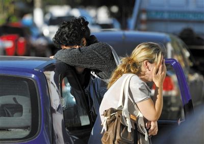 27日，遇難者親友在火災現(xiàn)場旁哭泣。