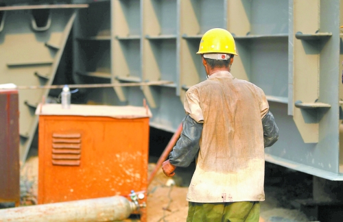 工地上，一建筑工人的衣服被汗水浸透。