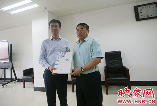 阿里云計算總裁胡曉明向河南省新聞出版廣電局局長朱夏炎遞交《中原云平臺交付手冊》。
