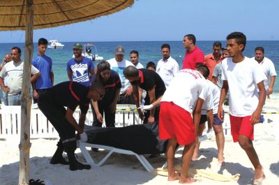 6月26日，在突尼斯蘇塞，救生員和醫(yī)務(wù)人員在發(fā)生襲擊事件的海灘運(yùn)送一名死者的遺體。新華社發(fā)
