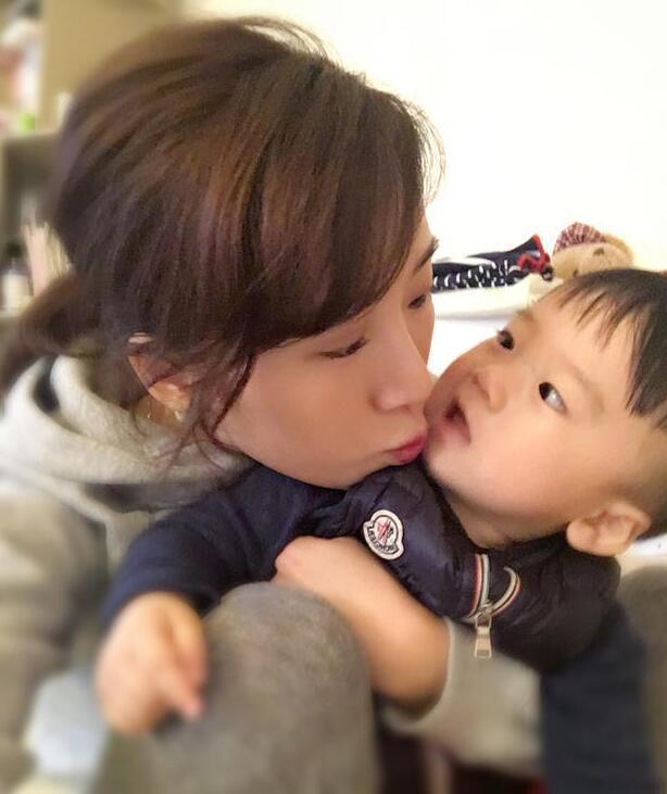 照片中李念狂吻兒子，小寶貝自顧自地玩著。