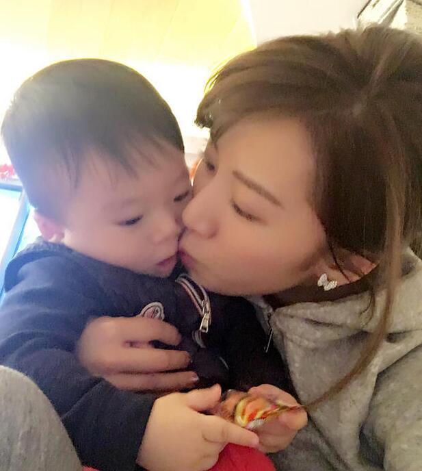 照片中李念狂吻兒子，小寶貝自顧自地玩著。