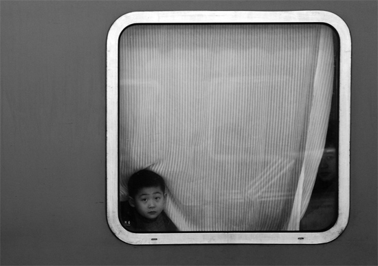 一個(gè)孩子把頭伸向窗外，他想再看送別的親人一眼