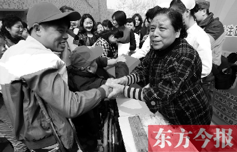 昨日，鄭大四附院的大樓前，“面人鄭”鄭玉芬（右）向前來捐款的殘疾人表示感謝