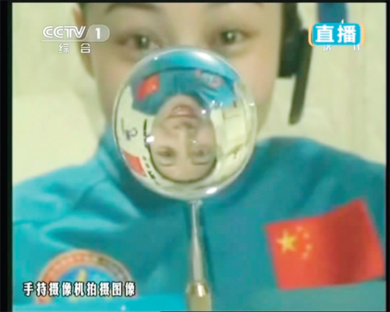 王亞平的倒影出現(xiàn)在水球中。新華社發(fā)（視頻截圖）