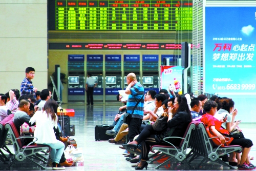 候車大廳溫度很高，一名乘客一手扇風(fēng)、一手擦汗