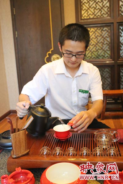 1、水壺里的水煮沸，李克勤把茶葉放進茶荷里，準備溫杯沖茶