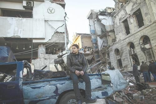 埃及曼蘇拉市警察局24日遭汽車炸彈襲擊，被疑是穆兄會(huì)的報(bào)復(fù)。圖為一名男子在被炸毀的警察局前。