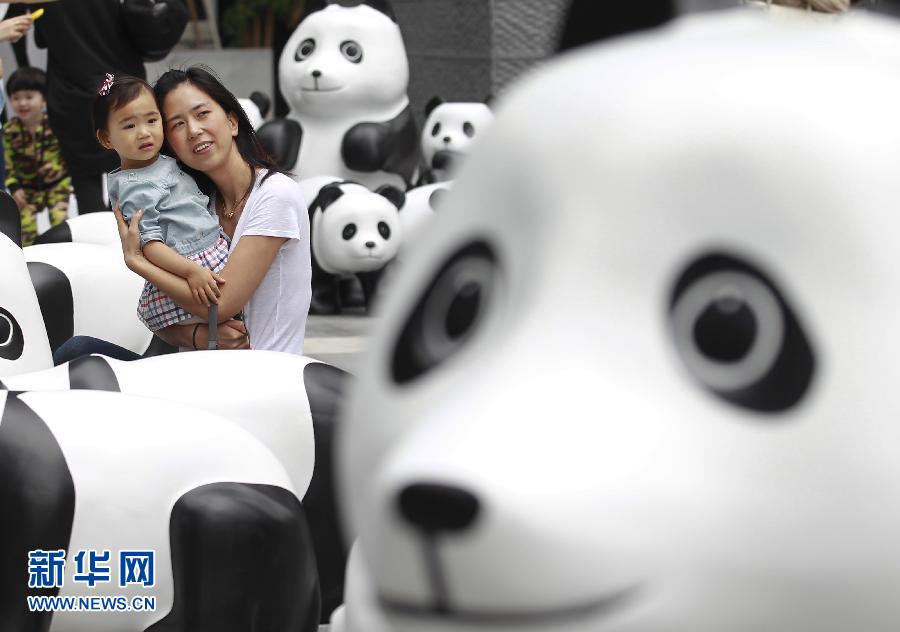 6月2日，一位家長帶著孩子在上海街頭和大熊貓模型合影。