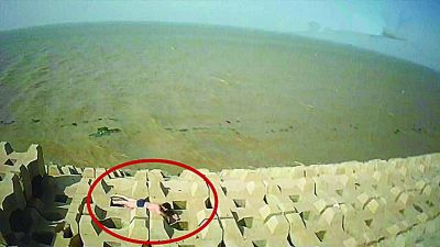 孫正龍游上岸，趴在海邊精疲力盡。