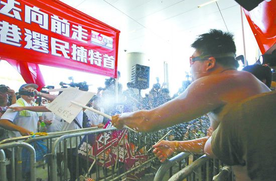 17日，在香港立法會(huì)外，一名反對(duì)政改的男子向支持派人群投擲標(biāo)牌。