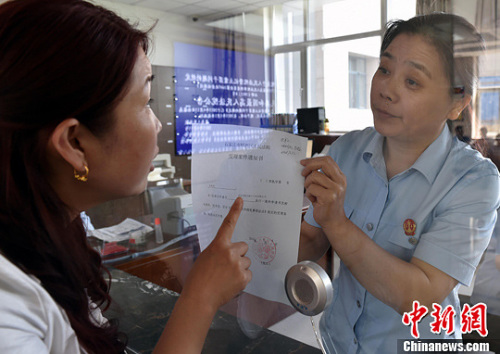 資料圖：2015年5月4日，河北石家莊市橋西區(qū)人民法院立案庭庭長齊燕正在為立案人辦理相關(guān)手續(xù)，完成整個過程只用了5分鐘。當(dāng)日是立案登記制改革首個工作日，該院共立案36件，立案率達(dá)到90%。中新社發(fā) 翟羽佳 攝