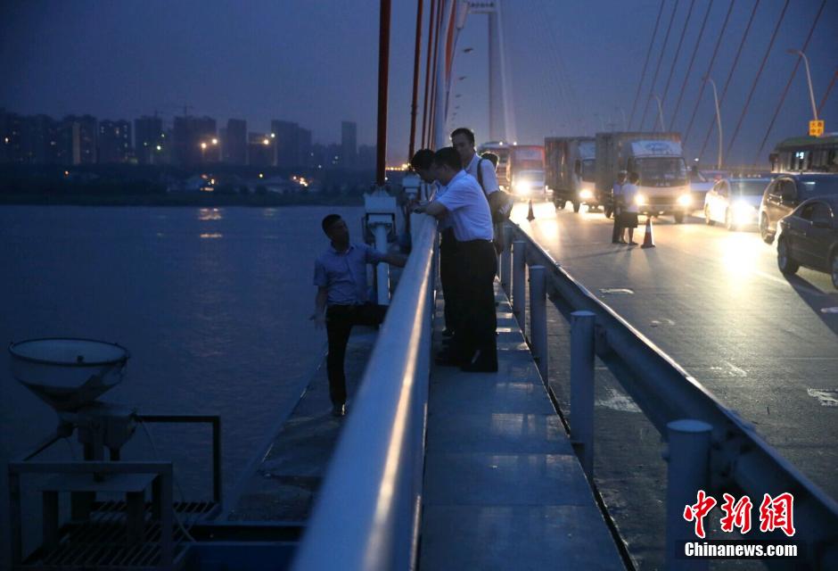 圖為武漢警方談判專家正在與翻爬至大橋外側(cè)護(hù)欄的劫持者談判。