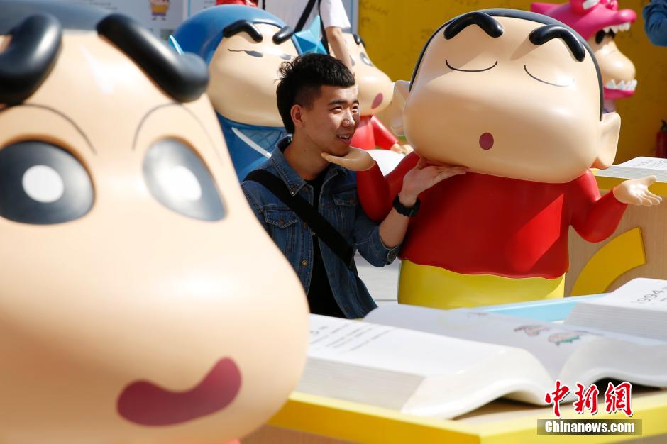 4月22日，游客與蠟筆小新合影?！跋灩P小新25周年紀(jì)念特展”日前在北京開展，吸引了不少市民游客。