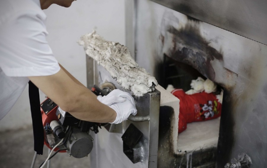 工作人員將狗狗推入火化爐。