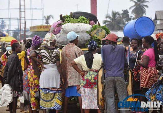 當(dāng)?shù)貢r間2014年8月14日，利比里亞蒙羅維亞，市場里的商人們圍著一輛汽車。