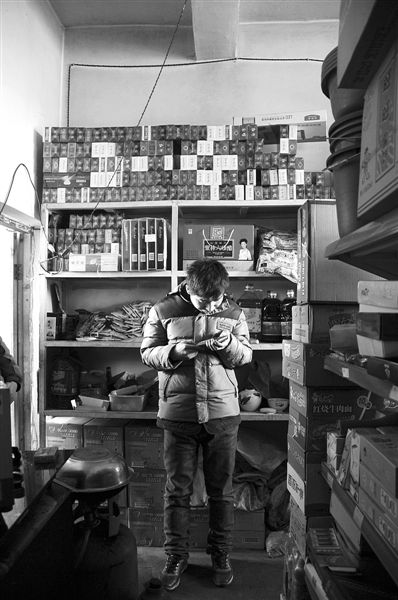 1月21日，周瑋在自家的超市里玩計(jì)算器。