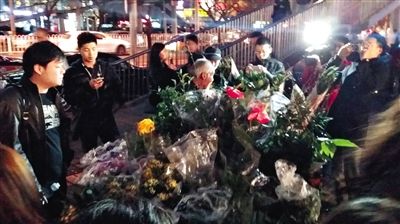 昨晚7時許，三里屯太古里西邊附近一過街天橋旁邊，聞訊而至的網(wǎng)友圍住了賣花老人，爭相買花。 網(wǎng)友“行者橙子”供圖