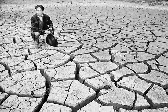 蹲在干涸的田地里，焦裕祿為饑餓的百姓揪心不已 《焦裕祿》劇照